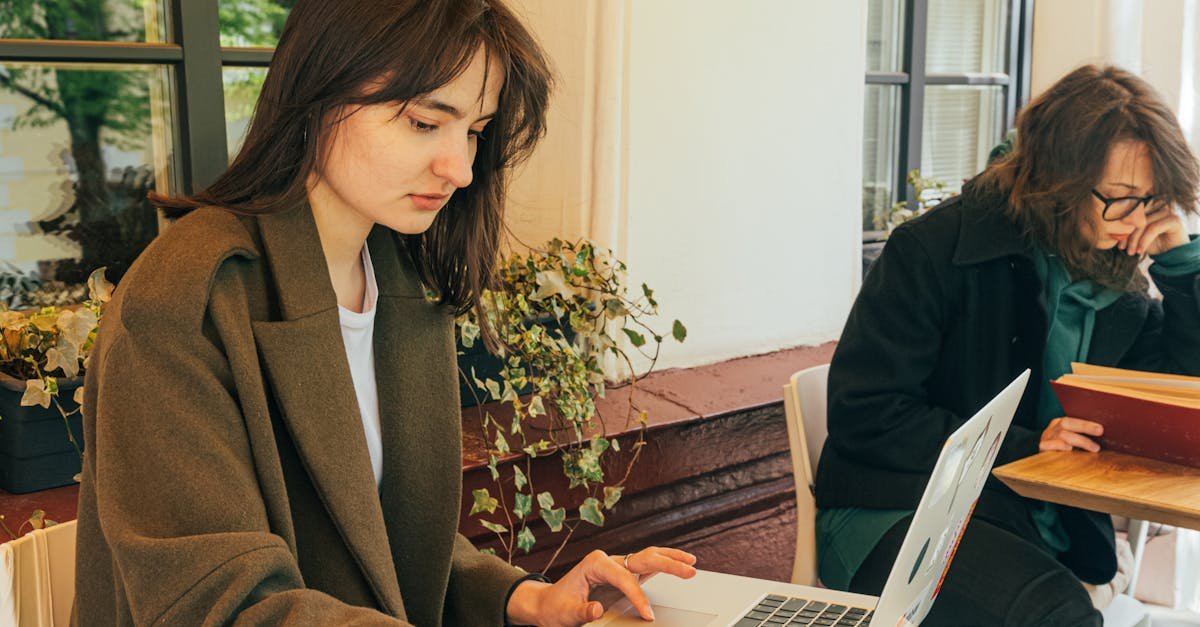 Woman in a caf&eacute; working on a laptop with a coffee and notebook, ideal for remote work concepts.